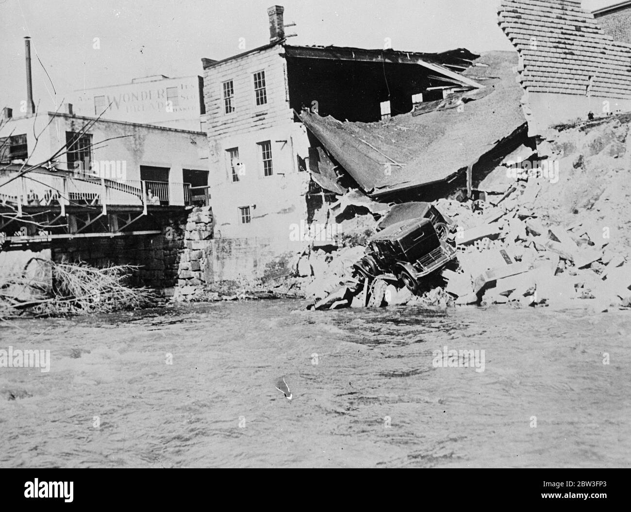 Buildings ruined by rushing torrent in United States floods - cars swept on debris . The wrecked buildings at Fitchburg , Massachusetts , with cars left high and dry on the debris . 1 April 1935 Stock Photo