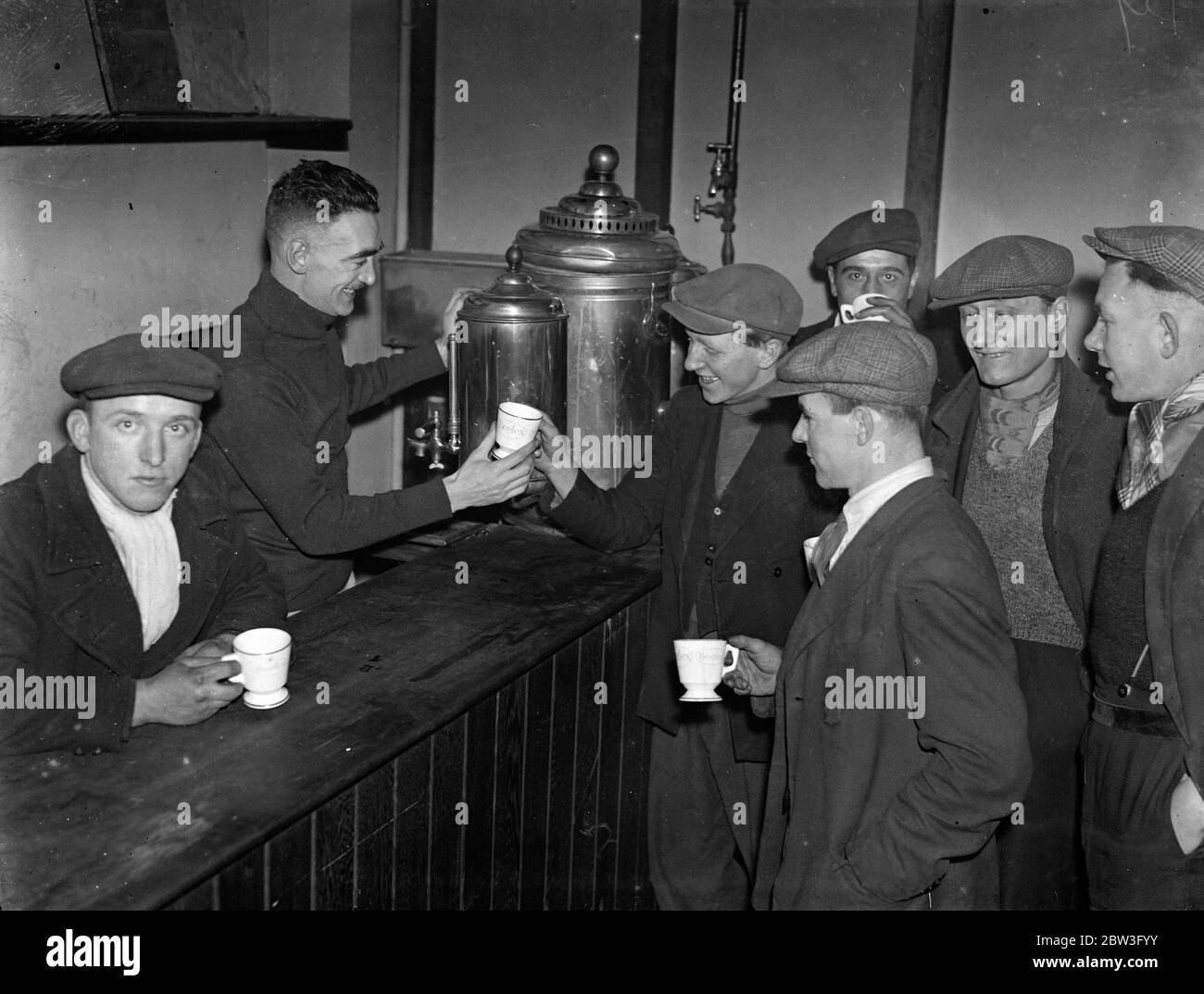 James Houston , novelist , runs centre for workless . Seen serving boys with refreshments at the Genville Hut in Battersea as they mend shoes . 5 February 1935 Stock Photo