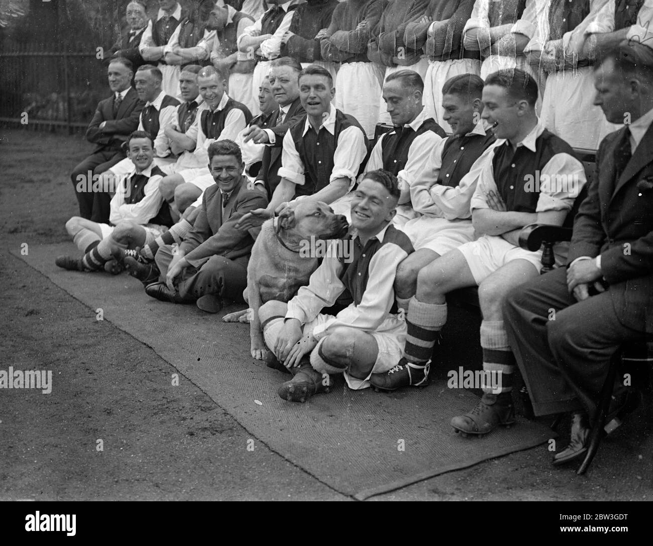 Arsenal Cup final players out at Highbury . The Arsenal Cup players practised at Highbury . Among them was Ted Drake , who had a try out after having recovered from injury . It is considered almost certain that he will be able to turn out at Wembley . Photo shows , Gunner the Arsenal ' s dog mascot , making a fuss of Peter Dougall watched by the other Arsenal players during a team photo shot . 7 April 1936 Stock Photo