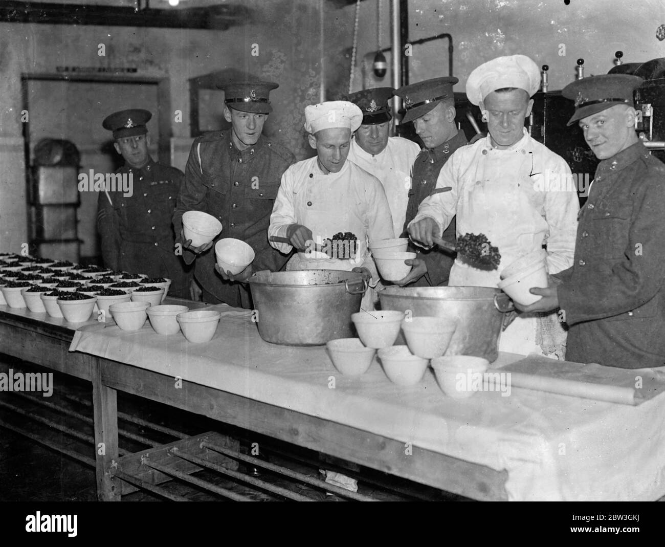 Woolwich barracks troops are making their own christmas pudding . For the first time men of the Royal Artillery at Woolwich Barracks are making their own Christmas puddings instead of buying them from outside . Six hundred men have to be catered for in the messroom and the work of preparing and mixing the puddings has already commenced . Liberal quantities of brand and stout are the most popular ingrediants . Photo shows , Cooks finding willing assistants at the Royal Artillery barracks , Woolwich , when the Christmas puddding column is drawn up on the kitchen table . 7 December 1935 Stock Photo