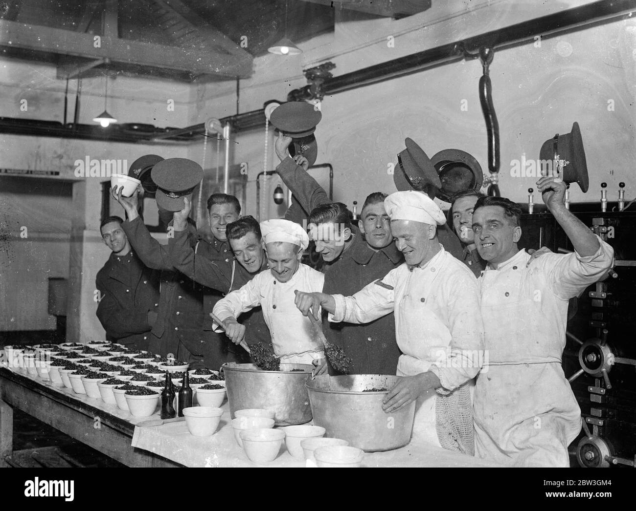 Woolwich barracks troops are making their own christmas pudding . For the first time men of the Royal Artillery at Woolwich Barracks are making their own Christmas puddings instead of buying them from outside . Six hundred men have to be catered for in the messroom and the work of preparing and mixing the puddings has already commenced . Liberal quantities of brand and stout are the most popular ingrediants . Photo shows , cheers for the cook and the puddings at woolwich barracks . 7 December 1935 Stock Photo