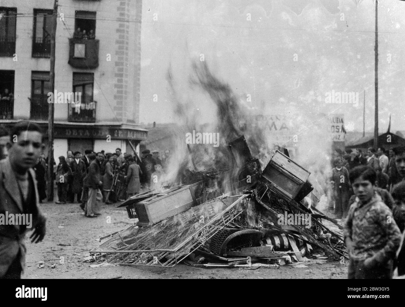 Madrid mob fires churches . Police open fire on rioters . The crowd surrounding the burning debris of a building after the rioters had fired it in Madrid . 15 March 1935 Stock Photo