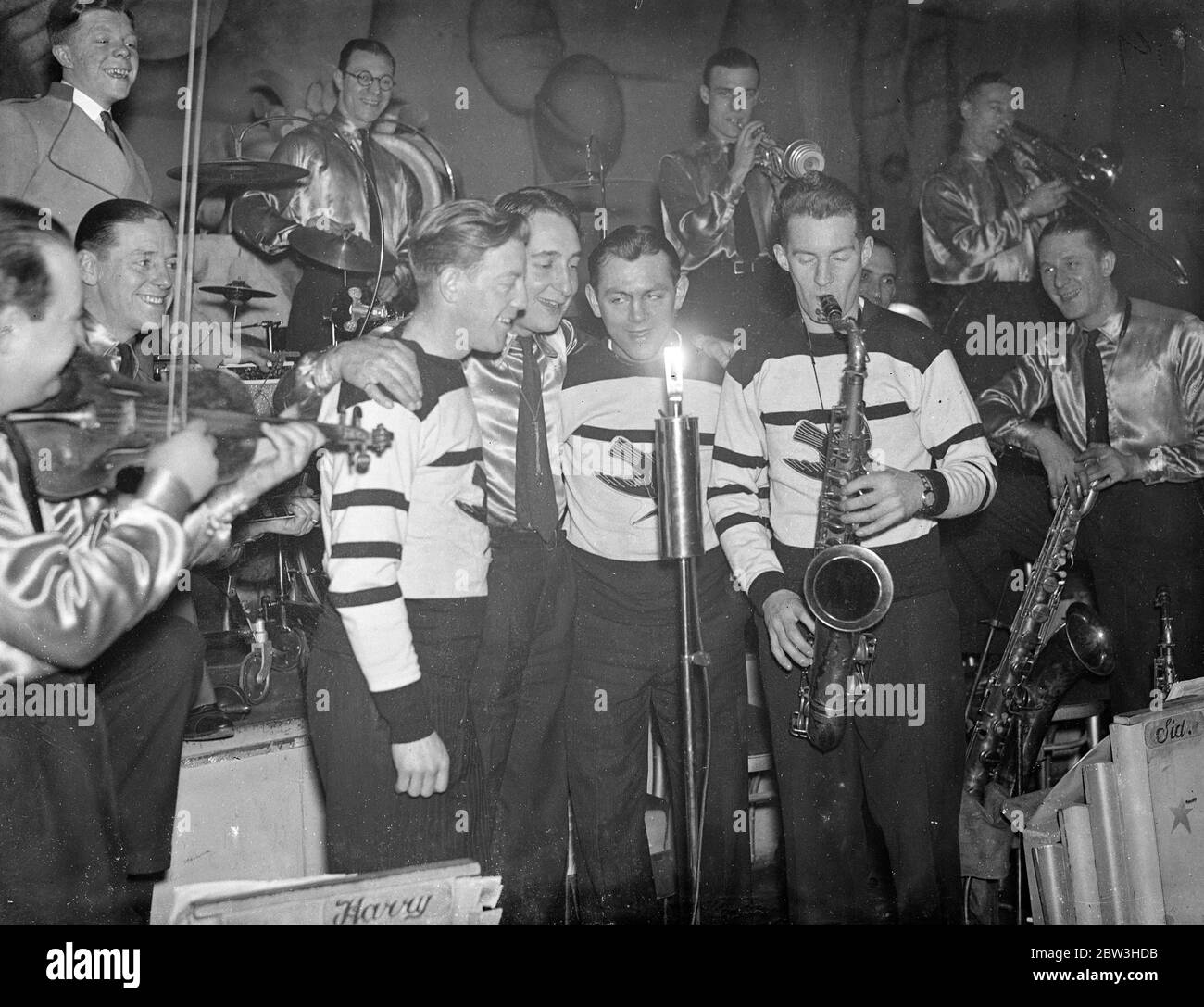 British Olympic ice hockey players to sing in dance band broadcast . Three of the ice hockey players who helped Britain to victory in the winter Olympic Games are to sing with the Romany Band in a broadcast next week . They are Jimmy Foster , goalminder , John Howard , forward , and Joe Beaton , who is captain of the Richmond Hawks . Photo shows , left to right , Jimmy Foster , Raymond Doughty , vocalists of the Romony band , Joe Beaton , and John Howard rehearsing in London for their broadcast . 23 March 1936 Stock Photo