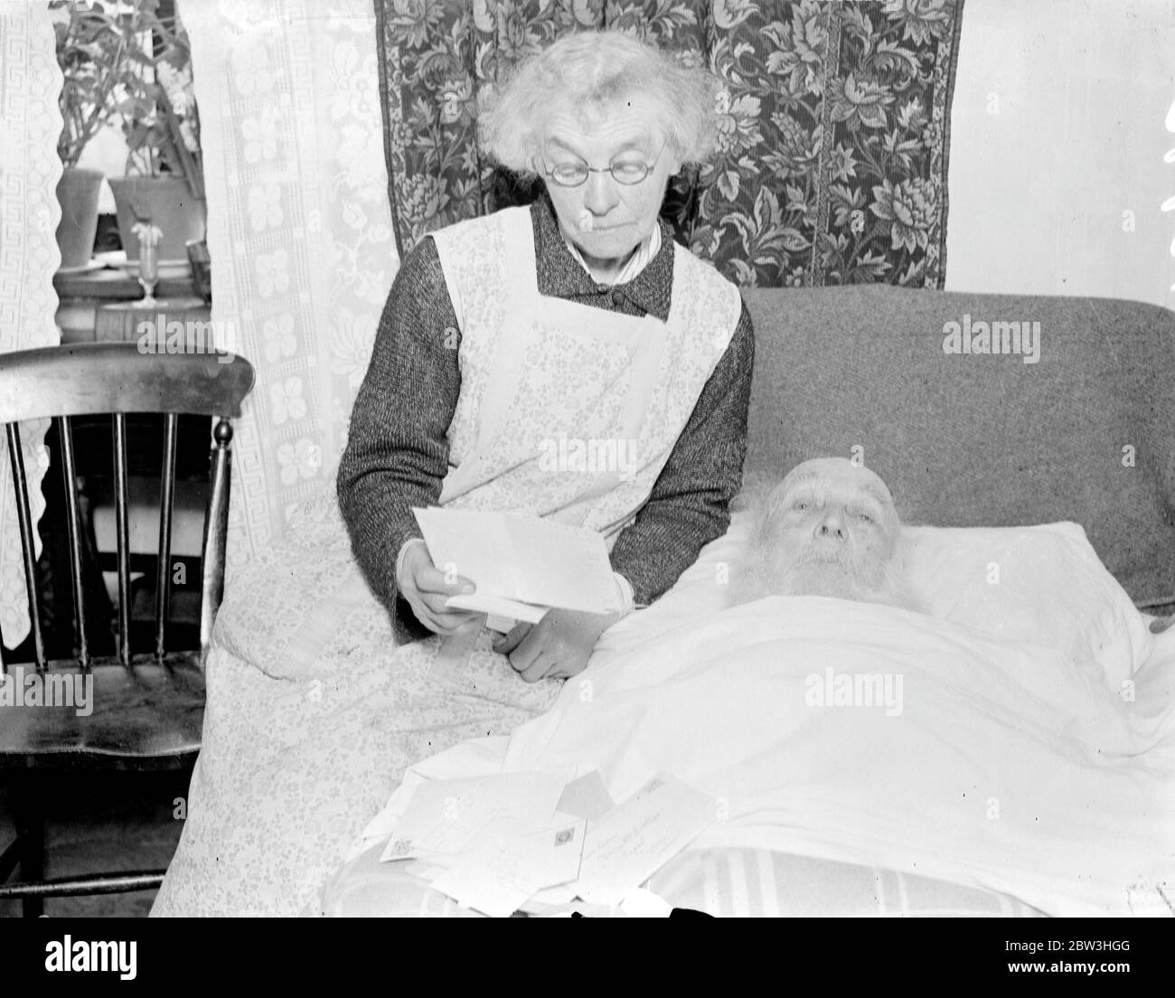 Mr William Lecey of Bennett ' s Cottages Capel , near Dorking is celebrating his hundred and second birthday . He is bed ridden , but not feeble and he complains because he is not able to shave himself . Photo shows Mr Lecey listening to messages of congratulations being read by his daughter , Miss Sarah Lecey .  9 February 1935 Stock Photo