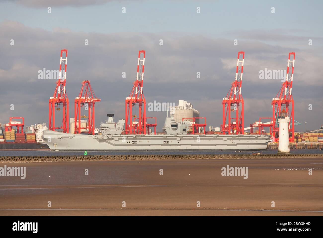 City of Liverpool, England. HMS Queen Elizabeth transiting past the red cranes of the Liverpool Container Terminal, on the River Mersey. Stock Photo