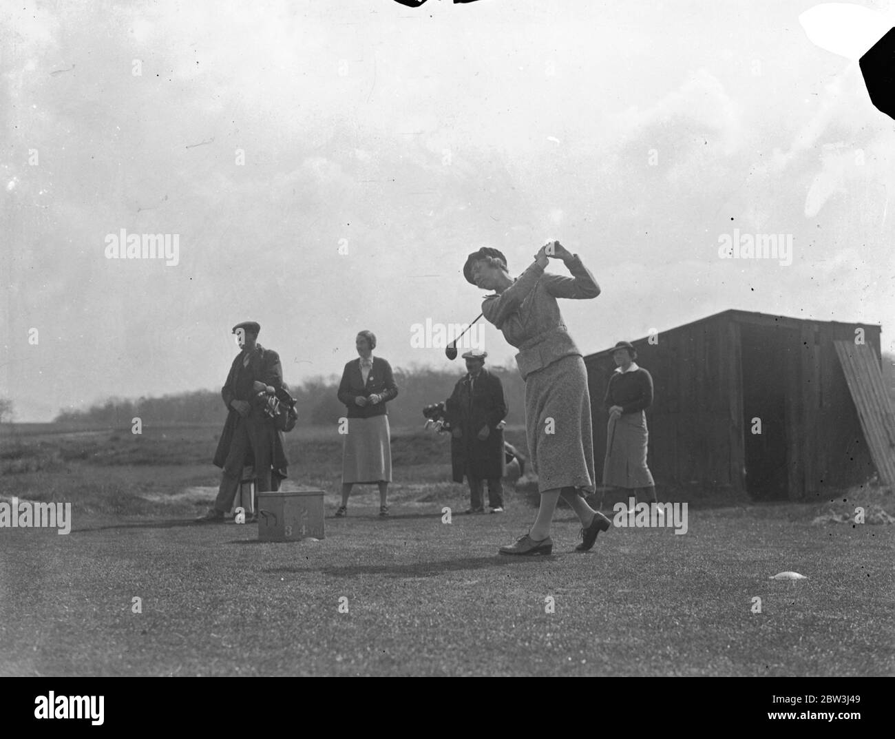American Curtis cup golfers play against English women at Sandy Lodge . Patty Berg watches Joyce Wethered . The United States women ' s golf team who are to defend the Curtis Cup against Britain on May 6 , met a team of well known English golfers who are not include in the British side in a friendly match at Sandy Lodge . Photo shows , Miss Joyce Wethered of England driving from the second tee watched by Miss Patty Berg , 18 year old American wonder golfer right ( right ) . 27 April 1936 Stock Photo