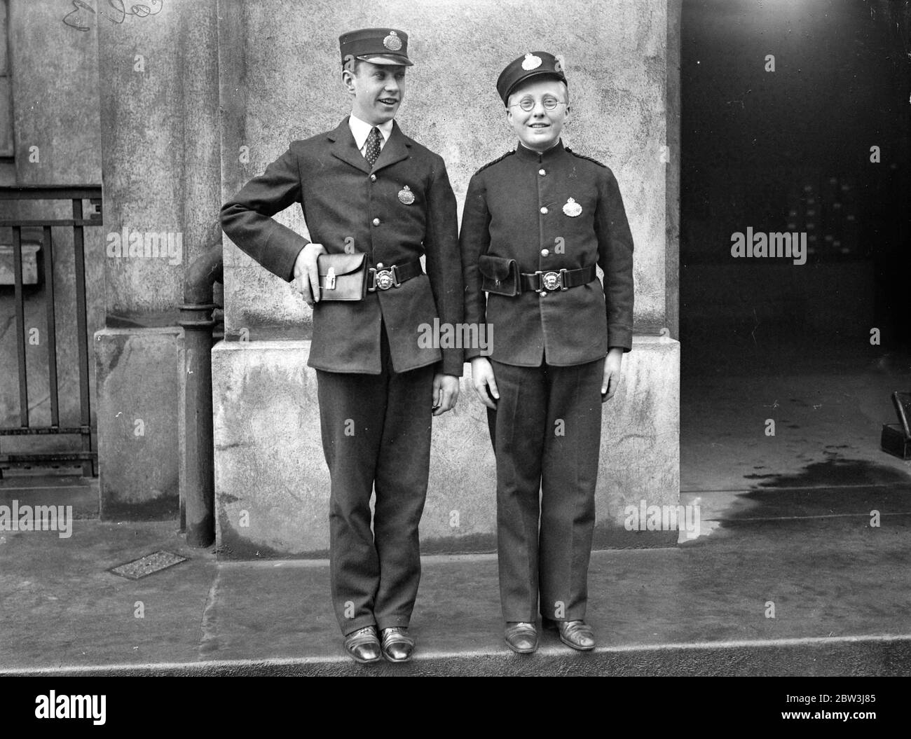 Smarter Uniforms For Post Office Messenger Boys - Open Collars Post Office Messenger boys are being equiped with smarter uniforms . The new design includes an open collar and a larger pouch to accomodate the  Greetings  telegrams . There is no braid on the shoulders . Photo shows : The new uniform ( with open collar ) compared with the old at Mount Pleasant 2 Jun 1936 Stock Photo