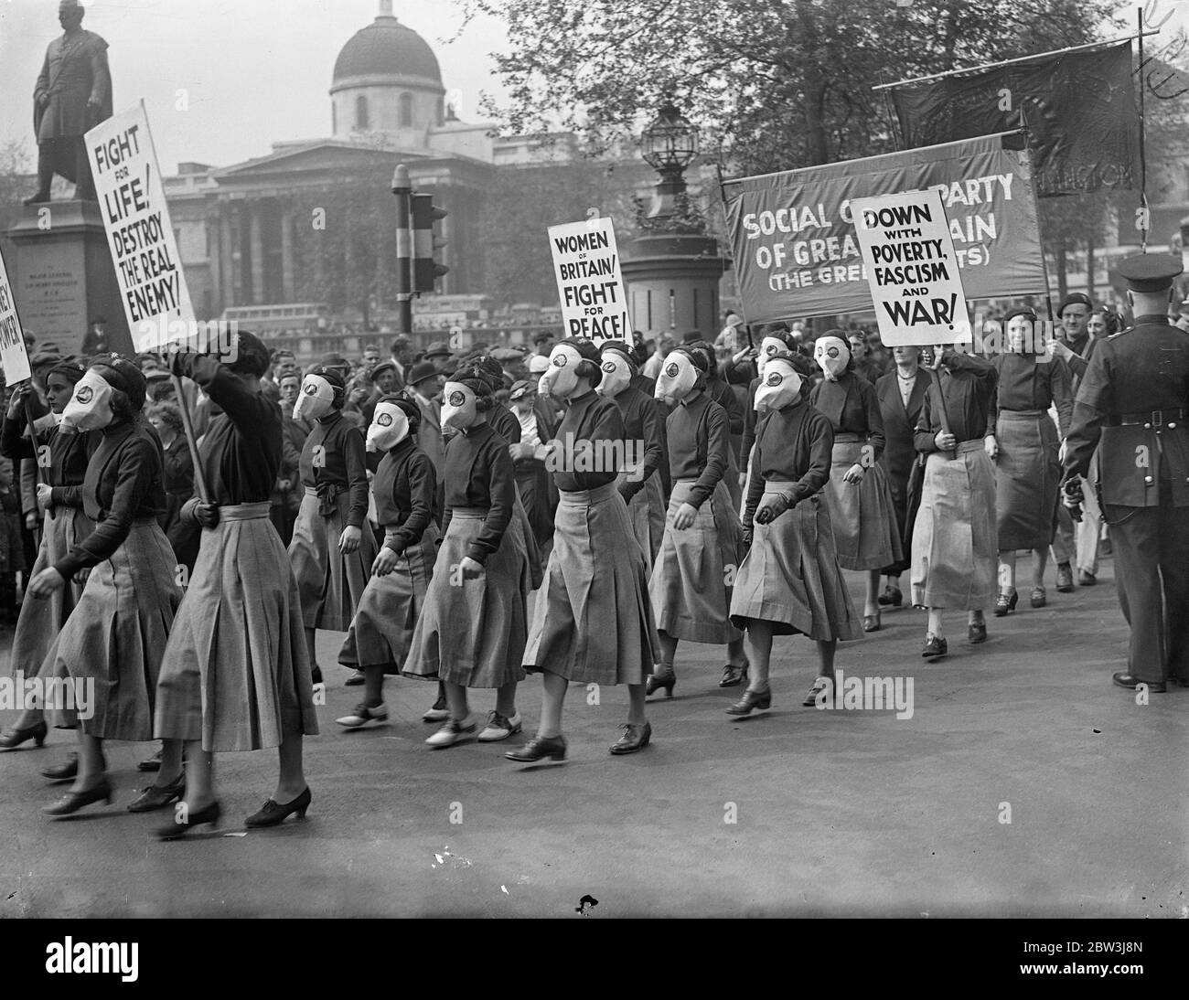 Masked women lead demonstrators in Trafalgar Square peace meeting . Led by women wearing representations of gas masks , thousands gathered in Trafalgar Square today ( Sunday ) for the great Peace meeting . Sylvia Pankhurst , the veteran suffragette , Monica Whately and Wal Hannington addressed the crowds . Photo shows , women in paper ' gas masks ' arriving at Trafalgar Square for the meeting . 17 May 1936 Stock Photo