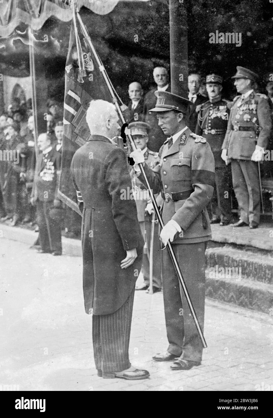 King of the Belgians presents new standard to ex servicemen in Brussels . King Leopold of the Belgians presented a new standard to the Croix de Feu , an ex servicemen ' s orginisation at the Grand Place in Brussels . Photo shows , King Leopold presenting the standard . 11 May 1936 Stock Photo