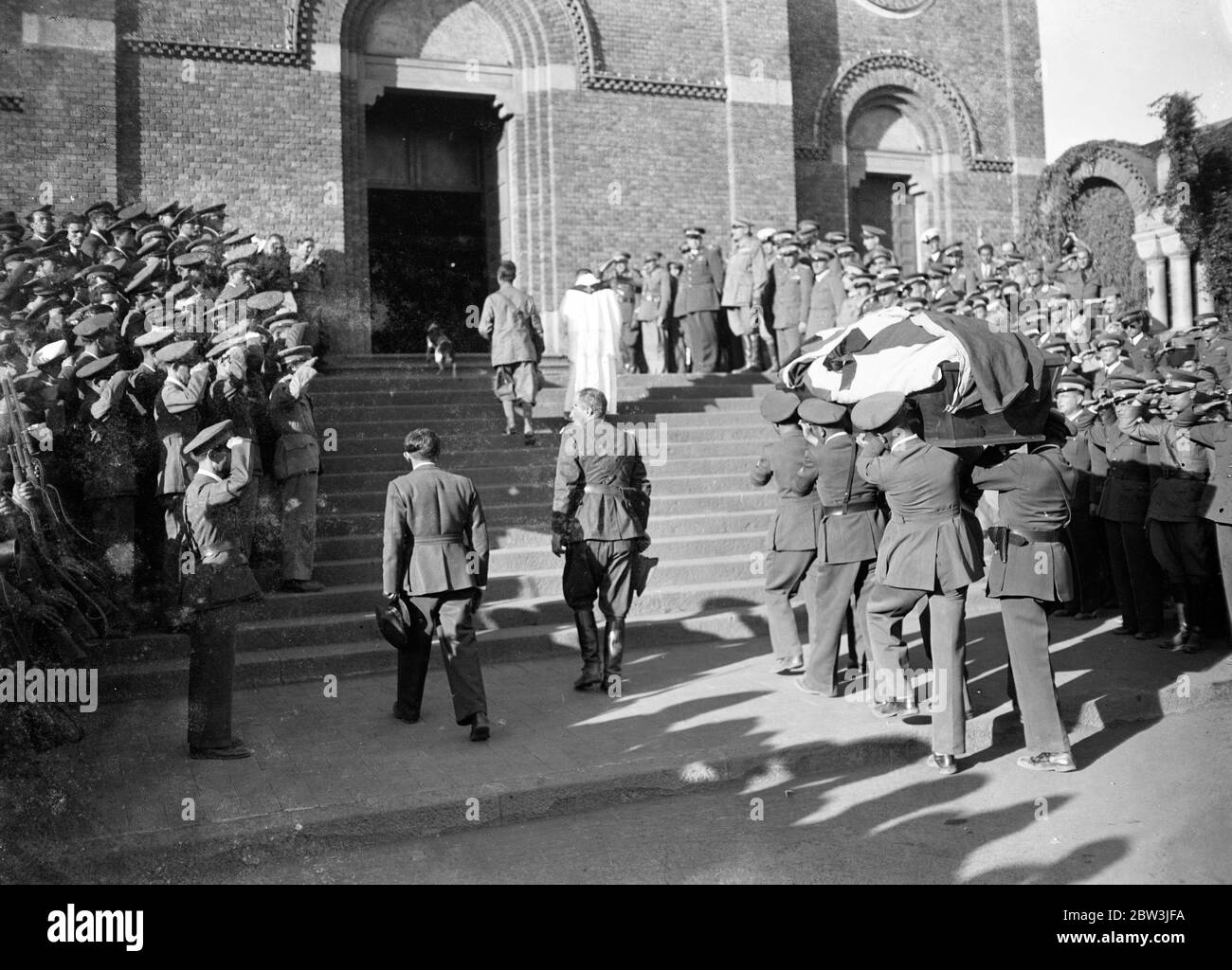 First airman killed in Abyssinian war given military funeral . The first airman killed in the Abyssinian war , Sergeant Birngo Dalmazio , a 24 year old flight sergeant and mechanic of the Italian forces who was wounded while on a bombing raid , was buried with full military honours in Asmara . Dalmazio , , who was hit by a dum dum bullet while flying with Lieutenant Sanze on a bombing raid on a decoy native camp in the valley between Enda Micael and Buja , was taken to hospital at Asmara but died from his wounds . Photo shows , the body of Sergeant Brirago Dalmazi being carried by comrades int Stock Photo