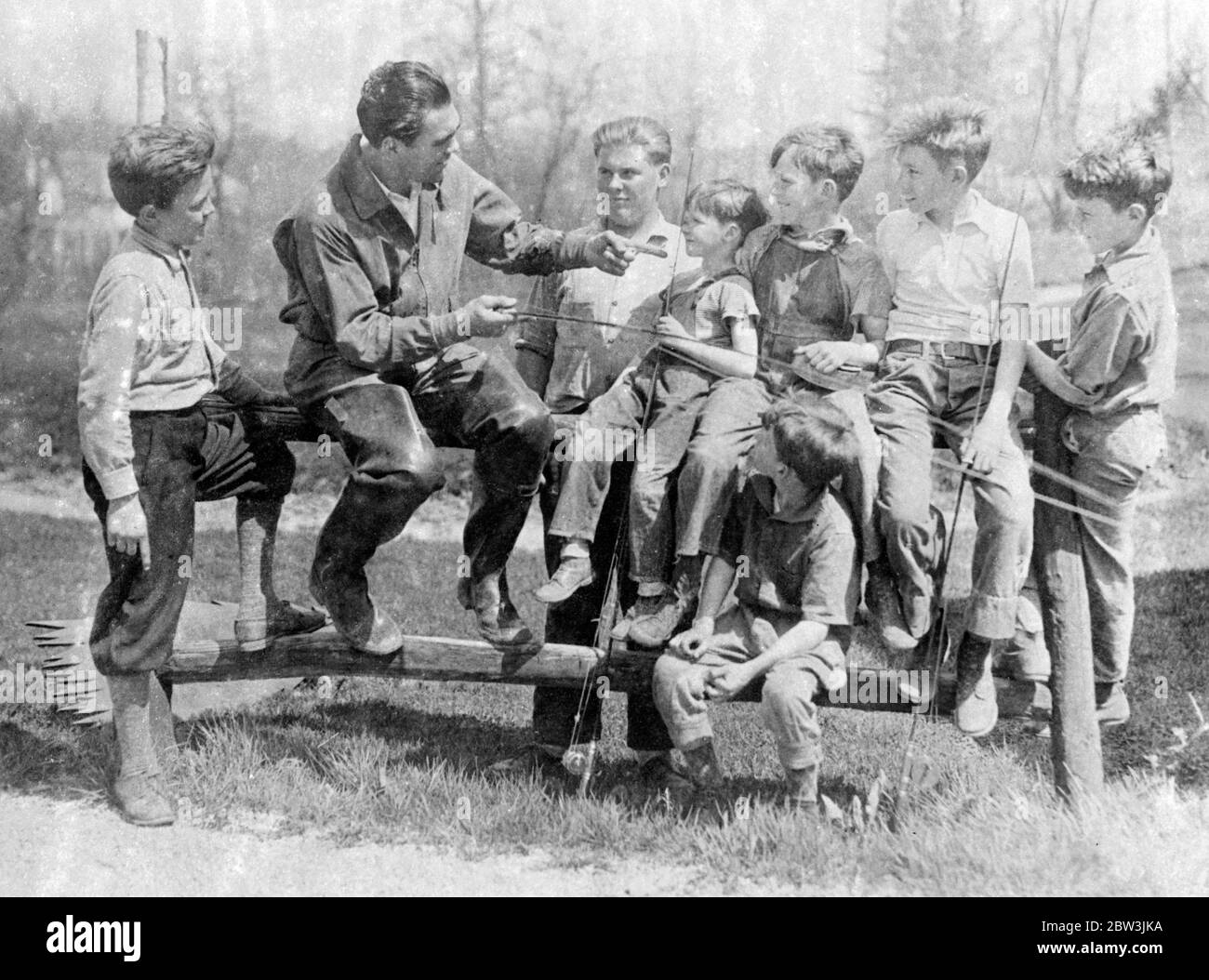 That One Was a Knock - out , Says Schmeling ! Fishing is part of Max Schmeling ' s training at Napanochi , New York State , for the German heavyweight ' s forthcoming bout with Joe Louis , America ' s coloured terror. Photo shows : Schmeling telling a fishing story to a group of young admirers at his Napanochi training camp . 9 May 1936 Stock Photo