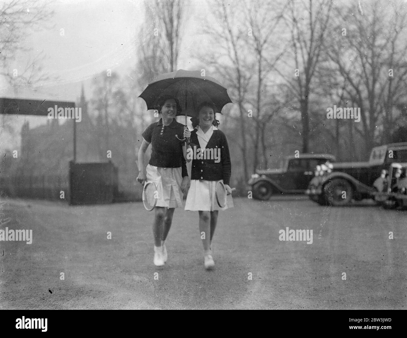 Arriving in rain for junior covered courts tournament . The Dulwich Covered Courts Club ' s junior tennis championship have opened . Photo shows Vera Dace , aged 14 and Pat Inga aged 11 arriving in the rain . 30 December 1935 Stock Photo