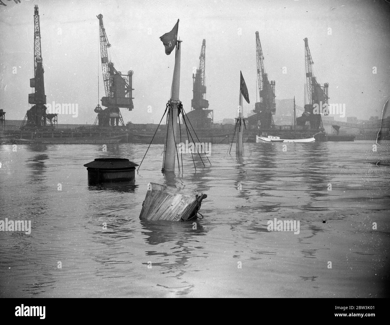 Buoys mark sunken Cgragside in the Thames . Only the masts , the top of the funnel and one of the ship ' s lifeboats are visible in Gallion ' s Reach , outside the Albert Dock , of the Tyne Tees Steamship Copany ' s vessel Cragside , ( 458 tons ) , which sunk after a collision with the S S Madura ( 9 , 032 tons ) belonging to the British Indies Steam Navigation Company . Photo showws , Wreck Buoys marking the positin of the sunken Cragside . 9 August 1935 Stock Photo