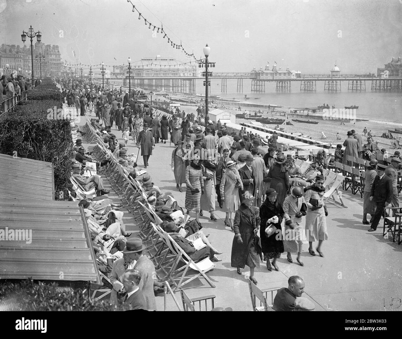 Holiday Crowds Find the Sun at Eastbourne Although London shivered in cold wind thousands of visitors found the sun in holiday mood at Eastbourne. Large crowds thronged the beach . Photo Shows : Large crowds walking in the sun on the promenade at Eastbourne today ( Whit - Sunday ) 31 May 1936 Stock Photo
