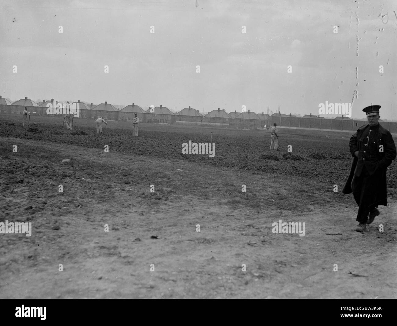 Convicts build houses in view of open road at Chelmsford . Seperated from the stream of terrif on the busy Sandford Road at Chelmsford , Essex , only by a prison patrol , a number of prisoners from Chelmsford Prison are building new homes for their warders . The men , most of whom are highly skilled , are carrying out the work under a plan known to the Prison Commissioners as the Chelmsford Experiment , designed to keep young prisonersaway from the ' old hands ' and to put them on to responsible work . It is hoped that the scheme will enable them to take their place once more in public life . Stock Photo