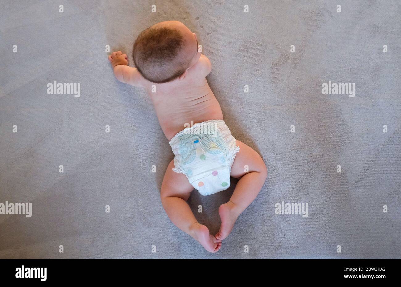 Young baby boy of 6 months in a nappie on a rug Stock Photo