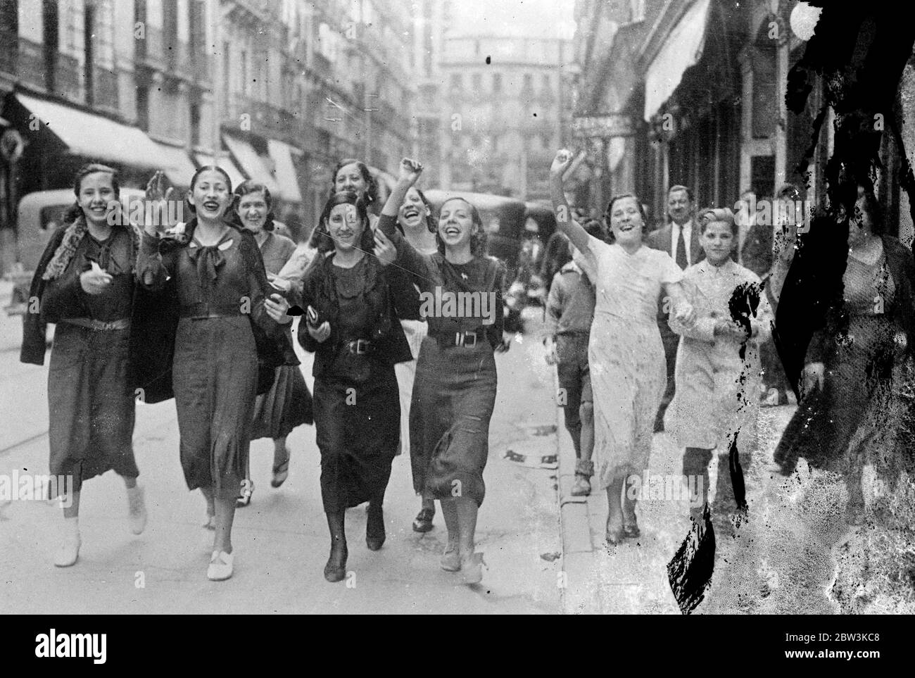 Girl dressmakers join strikers in Madrid , parade through town demanding general stoppage . Girls engaged in the millinery and dressmaking trades in Madrid have joined the strike movememnt which is sweeping the country and is involving workers in industries as far removed as coal mining , agriculture and even bull fighting , and has already cost many lives . The girls marched through the streets of the city shouting a demand that all workers in the dressmaking trades should join the strike . Photo shows , shouting girl milliners parading through Madrid . 18 June 1936 Stock Photo