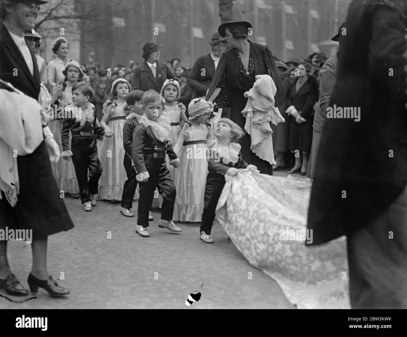 Tiny bridal attending at St Margaret ' s wedding . Two year old John Smiley , son of Sir Hugh and Lady Smiley , acted as page for the first time when wedding took place at St Margaret ' s Church , Westminster , of Miss Elizabeth Kerr Smiley and Mr Christopher Hussey . Lord Monsell , First Lord of the Admiralty and Lady monsell , lent Admiralty House for the reception . Photo shows two year old John Smiley attention is diverted as he follows the bride and groom . 23 April 1936 Stock Photo