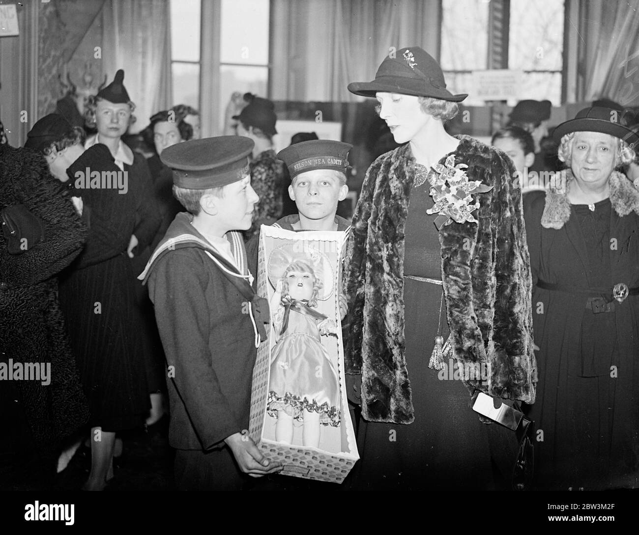 Lady Diana Cooper opens mariner ' s market in London . Lady Diana Cooper opened the Mariner ' s Market , organised in aid of the Missions to Seaman by the London harbour lights guild , at 23 Knightsbridge , london . Photo shows , Lady DianaCooper buying a doll from two sea cadets at the market . 23 November 1937 Stock Photo