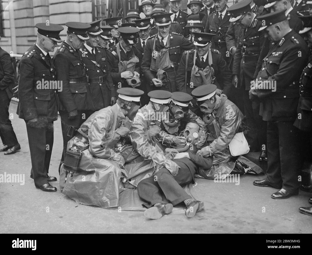 St John Ambulance officers take special course in anti gas service . Equipped with gas proof suits . Officers of the St John Ambulance Brigade receiving instruction on the treatment of a gas  victim  . Special gas proof clothing is worn by men attending the  casualty . 20 October 1935 Stock Photo