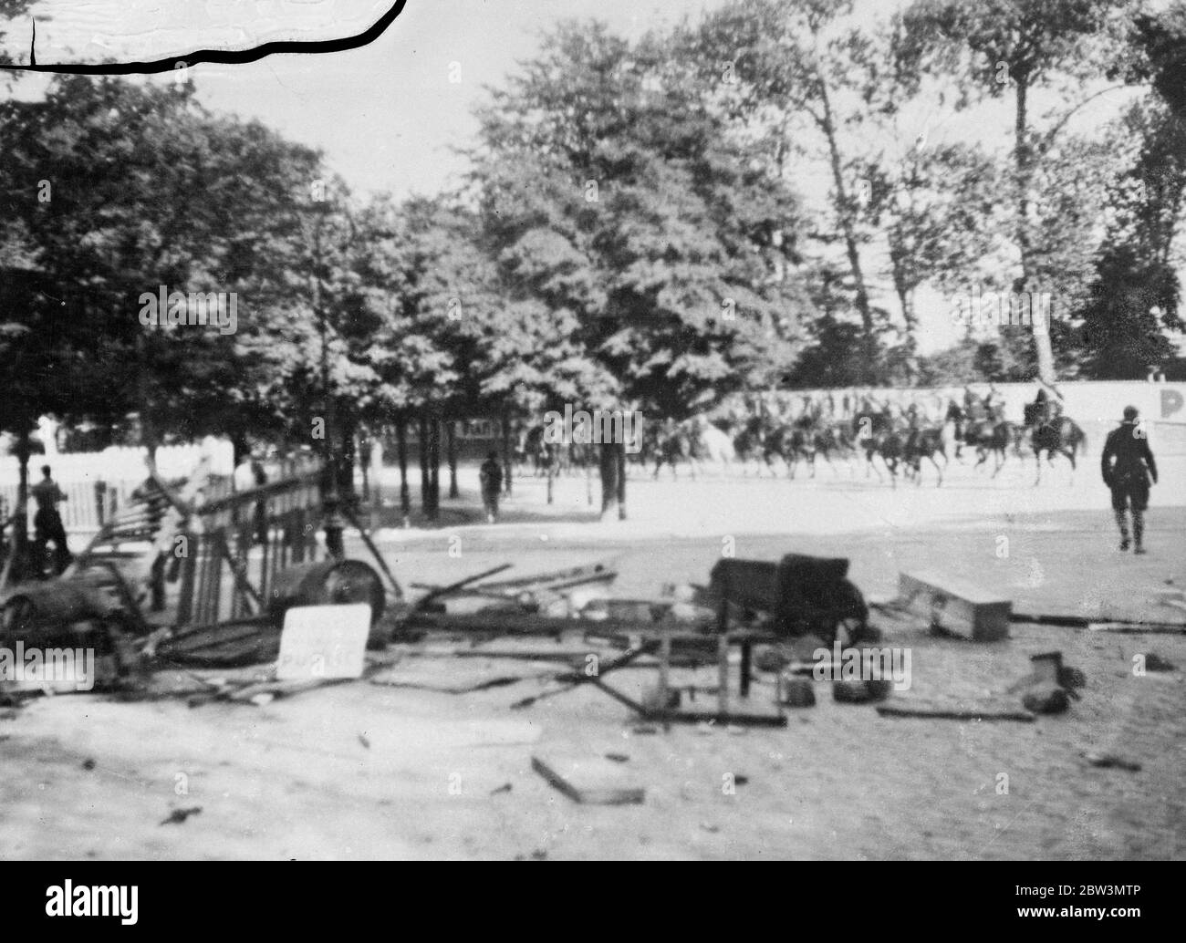 Brest rioters tear up paving stones as missles against police and troops . RIosters in Brest shipping strike caused through the French Goverment ' s econmy cuts . Photo shows French mounted troops pursuing rioters after capturing their barricade ( in foreground ) in the avenue Clemences , Brest . 8 August 1935 Stock Photo
