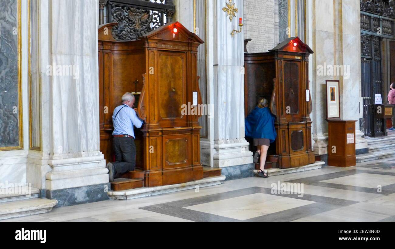 Two elderly people kneeling in front of the confessional in the Basilica Papale di Santa Maria Maggiore, Rome, Italy Stock Photo