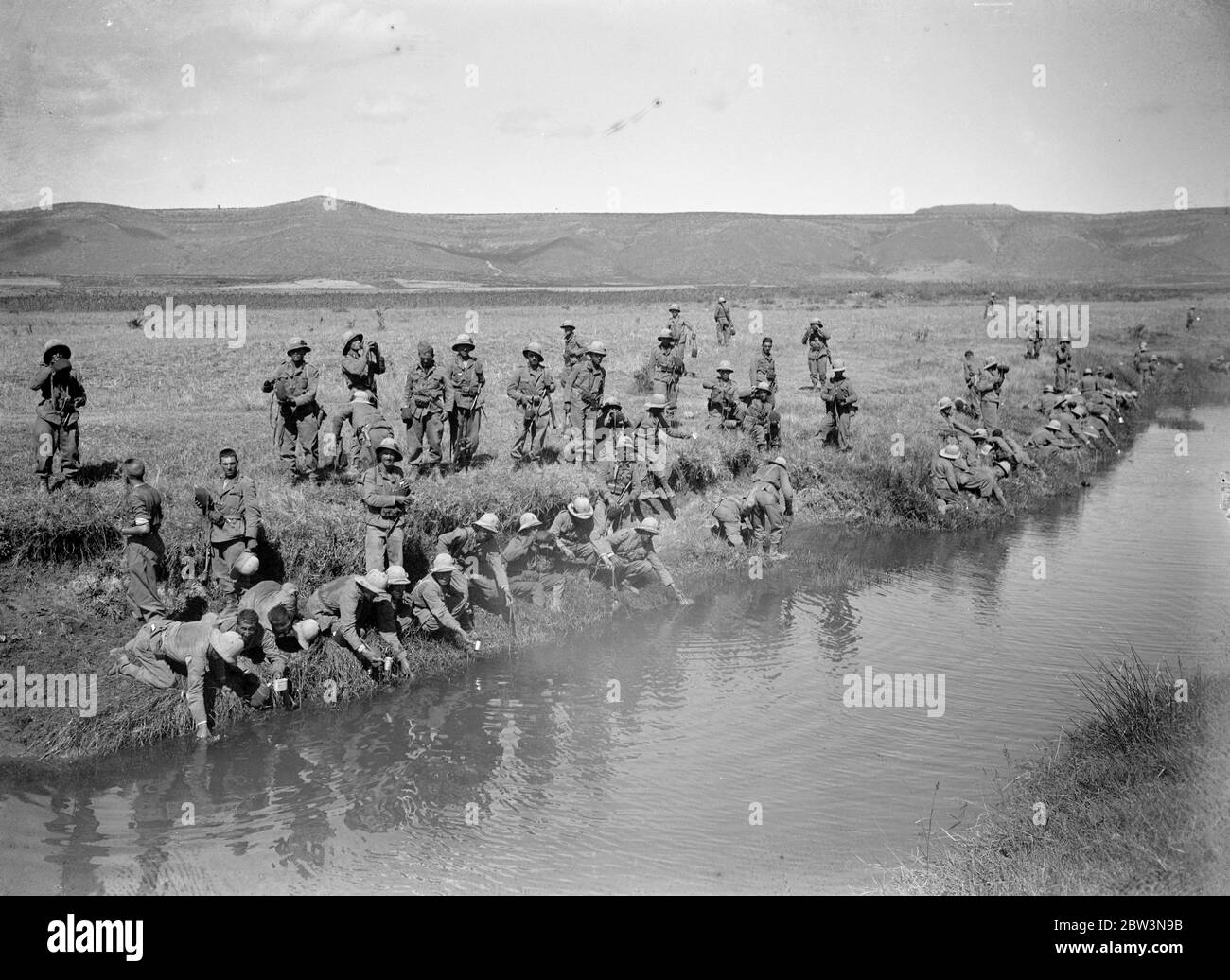 Troops slake their thirst at a stream . Iatalian soldiers who have been engaged in ' cleaning up ' operations on the northern fron near Makale , where the Abyssinians are now claiming a victory , greatfully quenching their thirst at a stream . Oppertunities to replenish water supplies are few and far between and a chance like this is not to be missed . 11 December 1935 Stock Photo