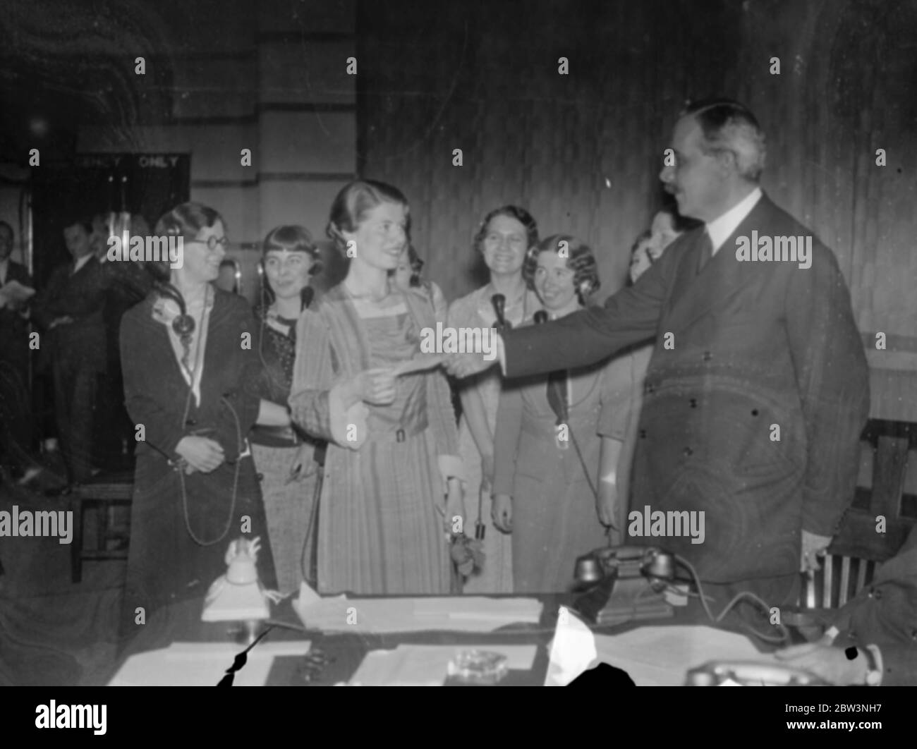 London telephone girl wins golden voice competition . M/S of Miss E. W. Cain sat at a switchboard reading poetry into the mouthpiece, other operators sit behind her. M/S of Postmaster General Major Tryon thanking the judges. M/S as the camera pans across the judges who are, Stuart Hibberd of the BBC (British Broadcasting Company / Corporation), Dame Sybil Thorndike, John Masefield, the Poet Laureate, Mrs Atkinson, chosen as the perfect telephone subscriber, and Lord Iliffe, they are all listening to Miss Cain speak through the telephone. Hibberd asks Sybil what she thinks of her voice and she Stock Photo