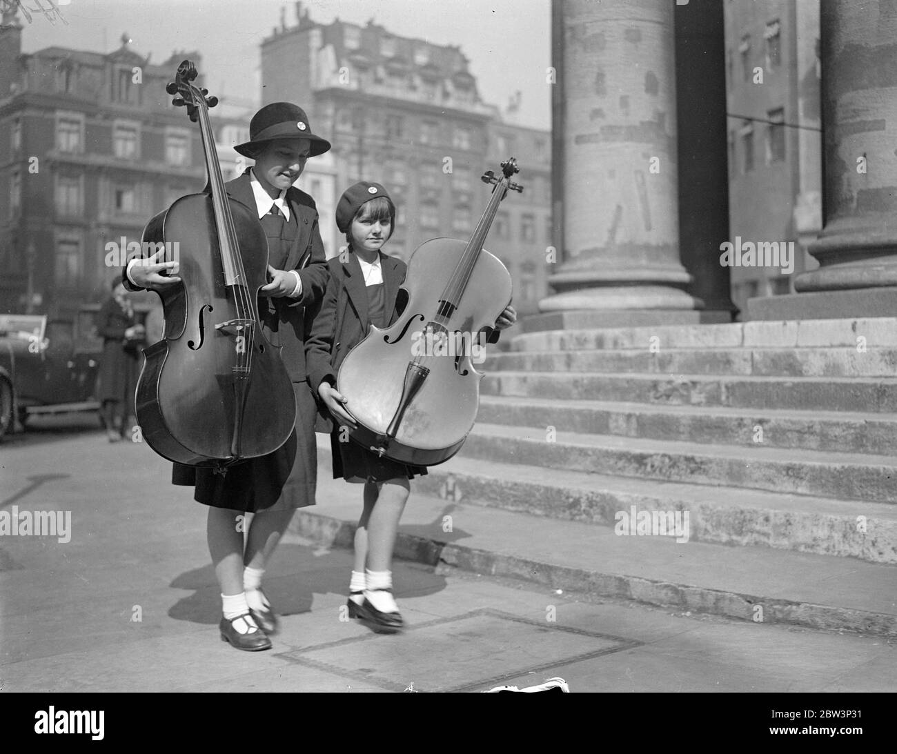 London ' s Musical Children Play At The Queen ' s Hall . Hundreds of young musicians are taking part in the School Orchestra and Junior Band Festival at Queen ' s Hall , London . Photo shows : Girl musicians arriving at the Queen ' s Hall with their cellos . 16 May 1936 Stock Photo
