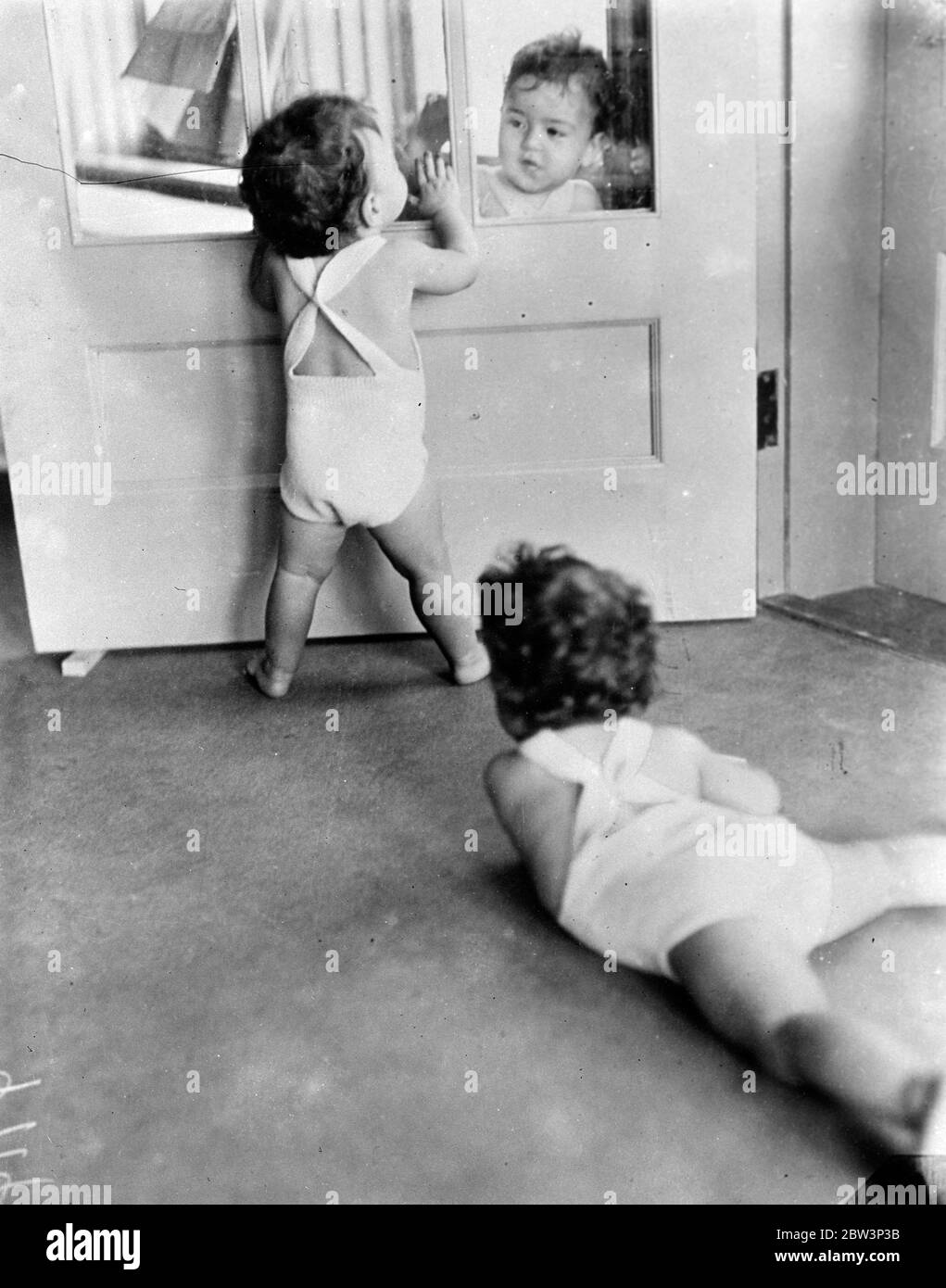 Quins investigate an invisible barrier . The glass in the door of the nursery at Callender , Ontario , provided an amusing half hour for the Dionne Quintuplets who were intrigued by the fact that they could see each other but not make contact . In this picture Yvonne and Annette ( on far side ) are seen feeling wonderingly over the glass whilst Emelie spreadeagled on the floor plays the role of interested spectator . 8 December 1935 Stock Photo