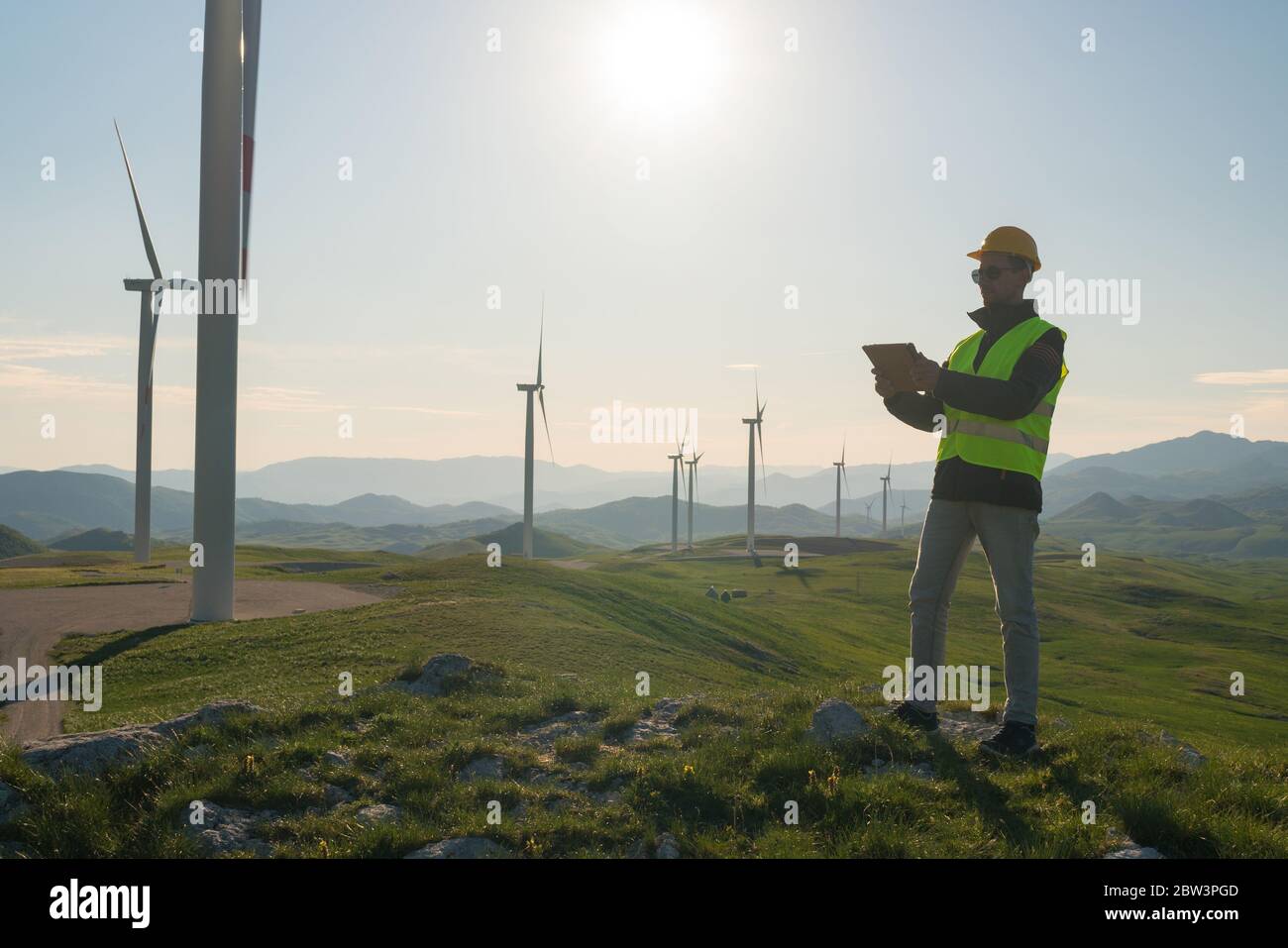 Technician Engineer in Wind Turbine Power Generator Station standing with a tablet in his hands Stock Photo