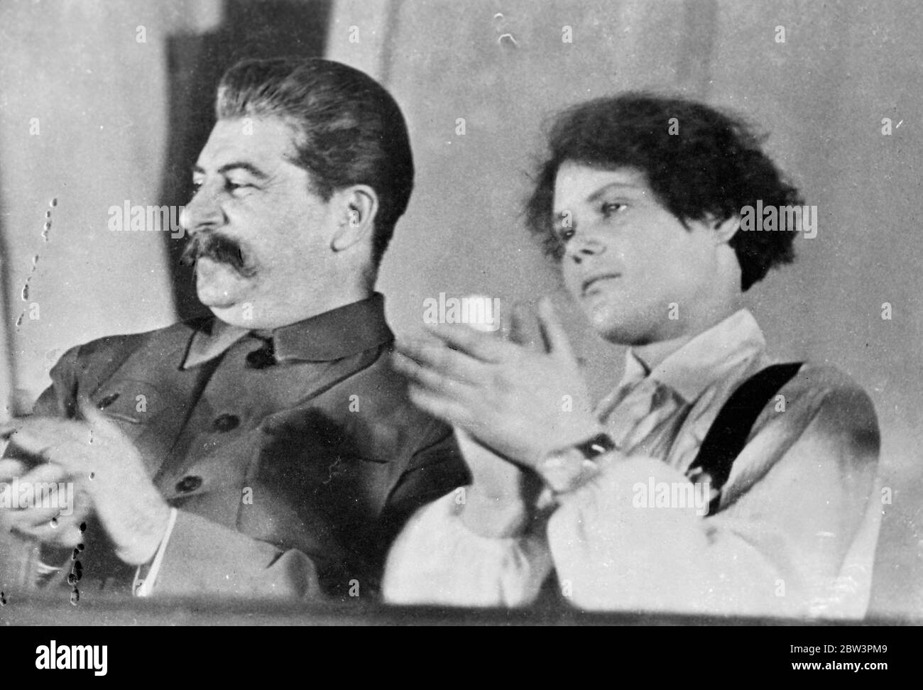 The leader smiles , his disciples applause . Jospeh Stalin , virtual dictator of Soviet Russia and idol of millions of workers , quietly smiles as he applauds with Mlle Maria Demchenko , one of his most ardent disciples , during the Tenth Congress of the Young Communist League at the Kremlin in Moscow . Maria is famous throughout the Soviet Union for a promise she made to Stalin . She gave her word that in 1935 she would harvest a record crop on the sugar beet collective farm on which she is employed . In the autumn of that year she had apply fulfilled her promise and the movement she started Stock Photo