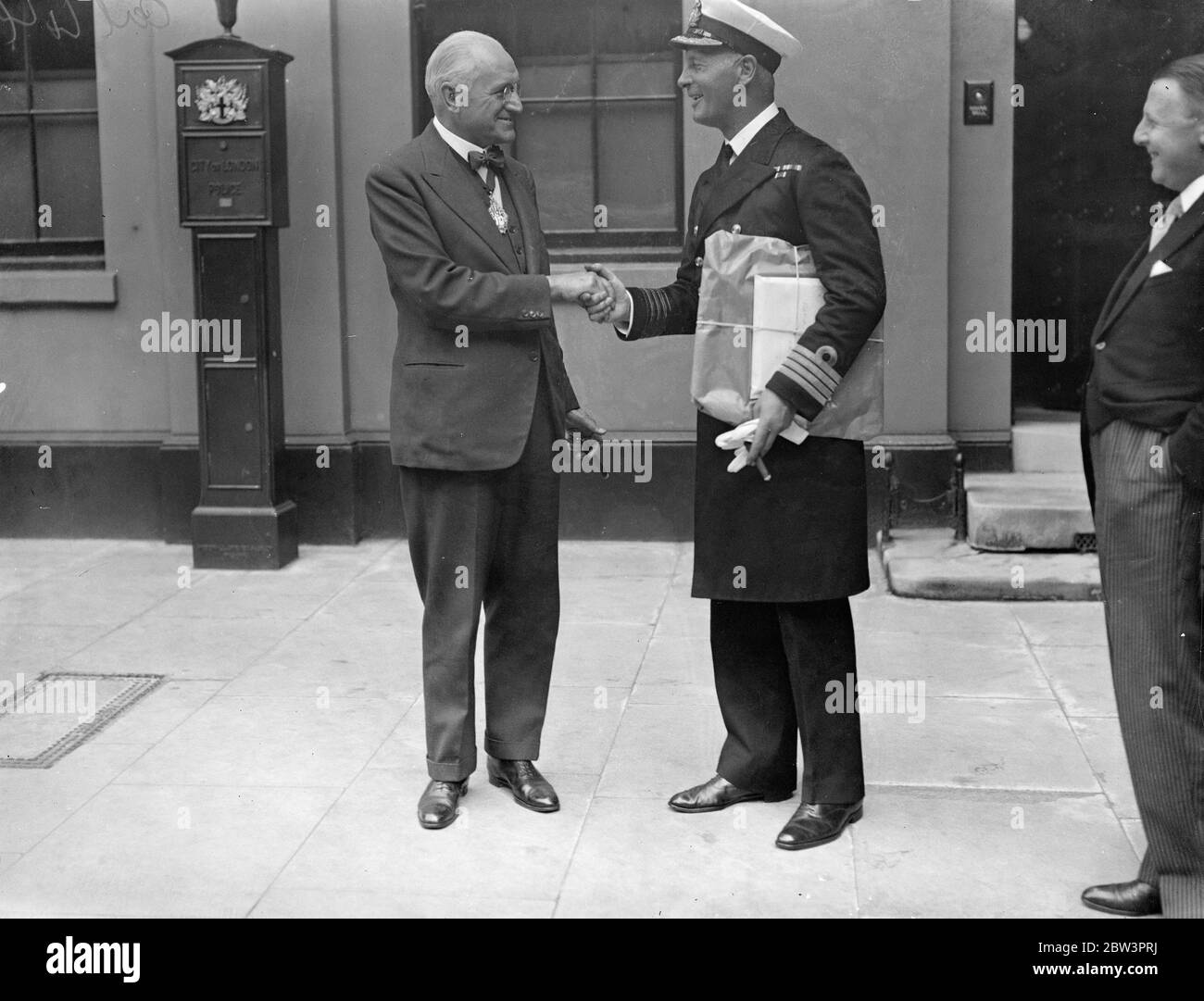 Captain of sloop  Londonderry  receives gift of plate from Irish Society at Irish Chamber , Guildhall Yard , London . Captain H E Jacomb of the newly built sloop Londonderry , with the plate , being congratulated by Mr George E Withers , FRIBA , City Councillor , Deputy Governor of the Irish Society , after the presentation . 25 September 1935 Stock Photo