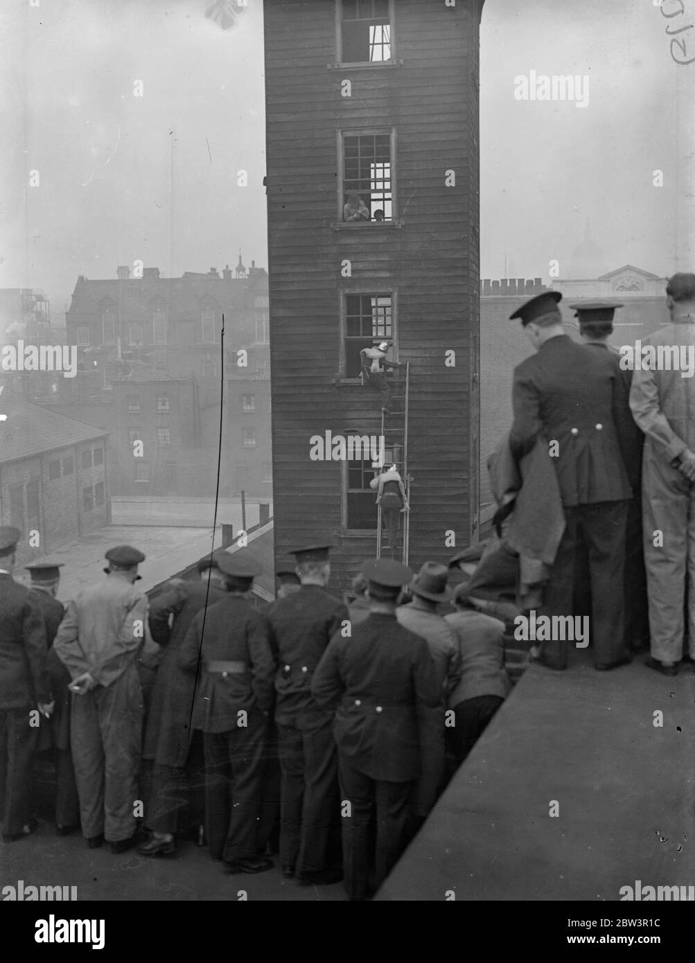 Rescues at finals of Fire Brigade escape competition . the finals of the London Fire Brigade escape competition took place at the brigade headquarters , Southwark . Photo shows , rescues from a burning building during the competition . 24 April 1936 Stock Photo