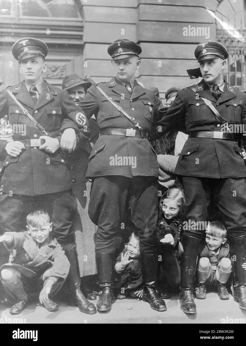 A peep at the chancellor . Children peering between the legs of burly SS men ( Nazi Black Guards ) who stood shoulder to shoulder in the Berlin streets as Chancellor Hitler passed through to make his National Labour Day ( May Day ) speech on the Lustgarten . 2 May 1936 Stock Photo