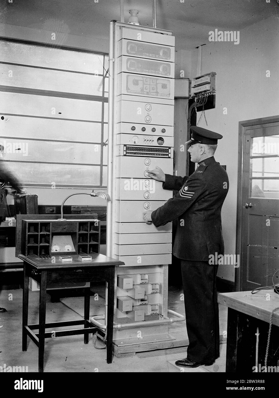 Scotland ' Yard ' s new radio station nears completion , will spread wireless net over London . Scotland Yard ' s new radio station , which will enable the police to place a wireless net over a radius of 40 to 50 miles of London , is nearing completion at Grove Park , Denmark Hill . Machines which record morse code in print , a voice frequency panel connected with Scotland Yard by landline , and short wave radio rceivers , have been installed . The ne station is also to play a leading part in the Home Office scheme for regional police radio stations . Photo shows , testing the voice frequency Stock Photo