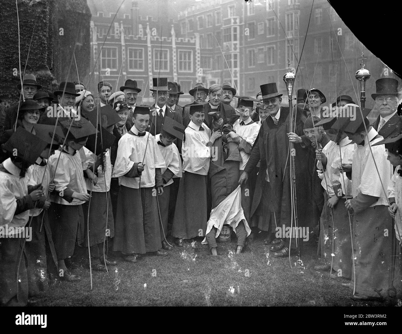 Choirboy Saw It Upside Down ! The rogation - tide ceremony of Beating the Bounds of St . Clement Dane ' s Church , Strand was carried out on Ascension Dey ( today ) . Photo shows : Inverting a choirboy during the ceremony . 21 May 1936 Stock Photo