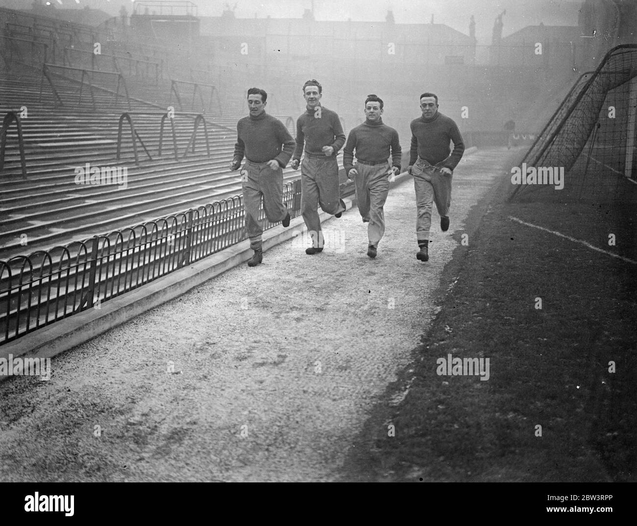 Frost stops Arsenal versus Bolton football match at Highbury . Players give demonstration . Because the ground was frozen and covered with ice the match between Arsenal and Bolton Wanderers at Highbury was cancelled . Instead , Arsenal players gave the crowd a demonstration . Photo shows , Joe Hulme , Frank Hill , Herbie Roberts , and Ray Bowden of Arsenal football club , sprinting round the ground . 21 December 1935 Stock Photo