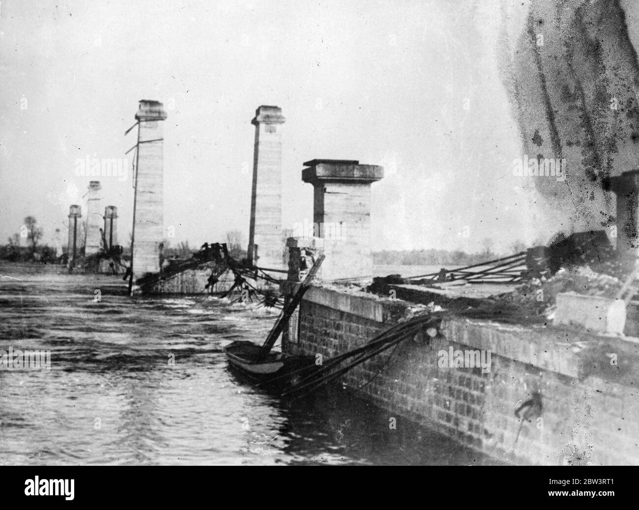 Nantes suspension bridge swept away by floods . Swept away by the raging torrets of the swollen River Loire , a big suspension bridge near the docks of Nantes , has collapsed . Nantes is suffering most from the continued floods , for the Loire has already risen several inches above the 1910 flood level . The inhabitants , with memories of the terrible inundation of twety five years ago , are in a state of panic . Hundreds of villages in France are under water as a result of the floods , which are worst for 25 years . Photo shows , the wrecked suspension bridge , swept away by the floods at Nan Stock Photo