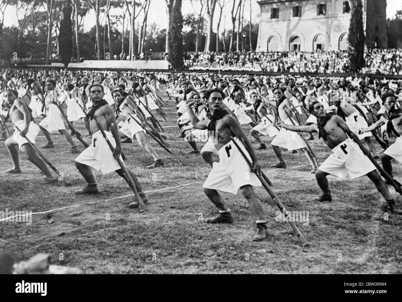 Italy ' s youth displays strength for Mussolini . In the midst of the greatest international crisis he has yet faced , Signor Mussolini took time off to watch a gymnastic display by a young Fascist in the Piassa di Siene , Rome . Photo shows , the gymnastic display before Mussolini . 6 September 1935 Stock Photo