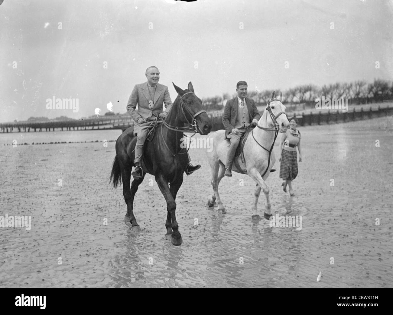 Mr Hore Belisha spends his holiday on horseback away from transport problems . Mr Leslie Hore Belisha , Minister of Transport and the man who controls all Britain ' s traffic is spending a holiday not on the roads , but on horseback at Ferring by sea , a secluded Little Sussex resort away from the traffic and transport problems . A keen horseman , Mr Hore Belisha rides every day on the downs and the seashore . Photo shows , Mr Hore Belisha galloping on the sands with Mr Richard Hallis at Ferring by Sea . 15 April 1936 Stock Photo