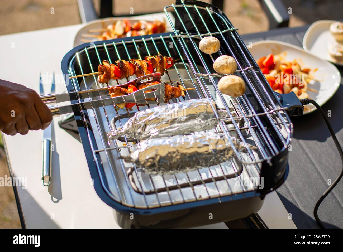 Grilling on a hybrid grill barbecue for electric or charcoal. Marinated raw chicken skewers on wooden skewers with bell pepper and onion Stock Photo