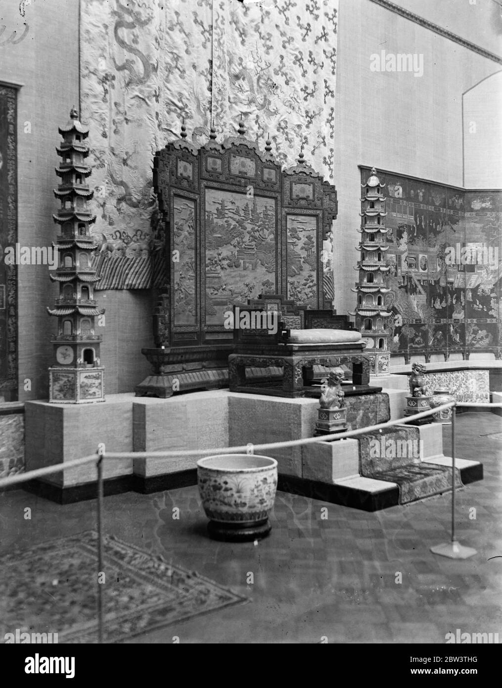 Chinese art exhibition ready for the opening . An Emperor 's throne of the Ch'ing Dynasty . It is of teakwood with decorations of cloisonne enamel and is lent by the Chinese Government . Also in the picture are pagodas , a silk carpet and other treasures . 26 November 1935 Stock Photo