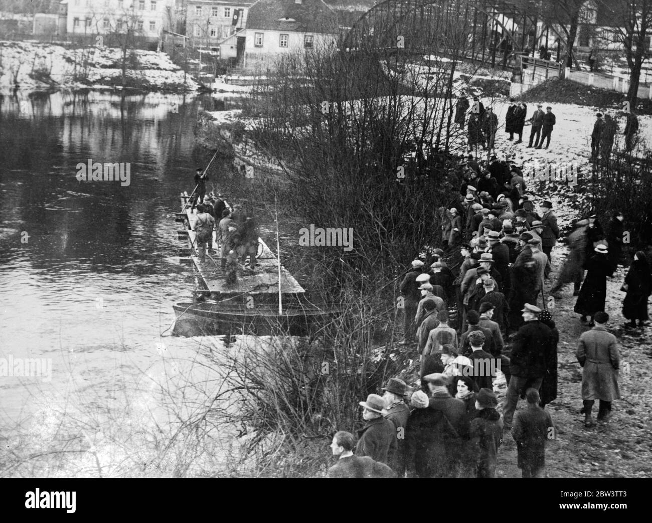 Raft used in river search for victims of German train disaster . Rescue workers are searching from a raft the wates of the River Seale near Gross Heringen , Thuringia , Germany , for bodies of victims of the disastrous railway smash on a bridge over the river which resulted in the loss of 33 lives and injury to scores of people . Photo shows a crowd watching the search of the River Saale near Gross Heringen . 28 December 1935 Stock Photo