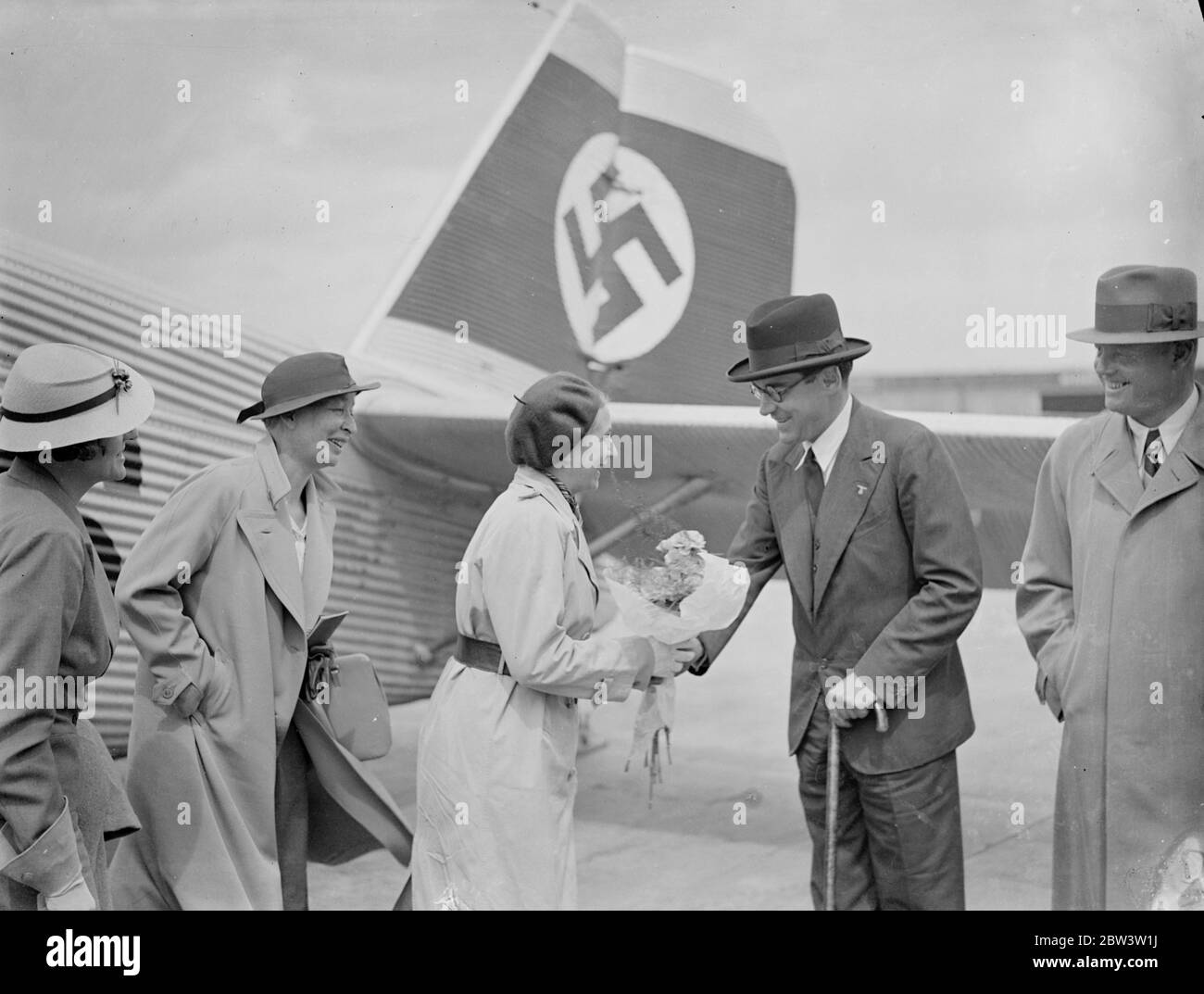 Nazi perfect woman arrives by air to attend London conference . Frau Gartrud Scholz Klink , Germany ' s perfect Nazi women , arrived at Croydon Aerodrome by air , to attend the Third International Congress for Social Work in London . Frau Scholz Klink , who is not yet 40 is here of the National Socialist womanhood . She fulfills all the idols of Nazi womanhood , and is an ardent advocate of the ' back to the kitchen movement . She was welcomed by Prince von Bismarck , German Charge d ' Affaires in London . Photo shows , Frau Gatrud Scholz Klink chatting with Prince von Bismark on arrival at Cr Stock Photo