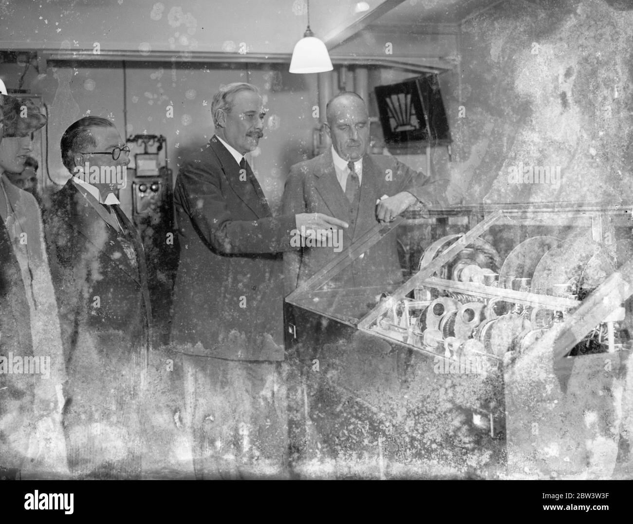 P . M . G . And Astronomer Royal Inaugurate Telephone Talking Clock . The Postmaster - general , Major G . C . Tryon M . P . and the Astronomer Royal , Mr . H . Spencer Jenes , Inaugurated the Talking Clock Service at the Tandem Telephone Exchange building in Holborn . The service is now available to London telephone subscribers who will be able to obtain the time by simply dialling TIM . Photo shows : The Postmaster - general , Major G . C . Tryon , explaining the mechanism of the talking clock to Mr . H . Spencer Jones , Astronomer Royal . 24 Jul 1936 Stock Photo