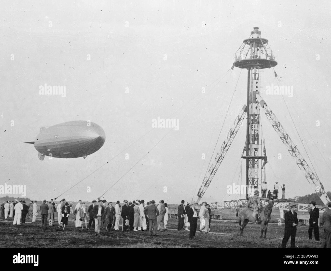 ' Hindenburg ' Germany ' s giant airship , at Rio De Janeiro . These pictures just received in London by air , show the ' Hindenburg ' , Germany ' s gigantic new airship , at the Santa Cruz aerodrome Rio de Janeiro agter her maiden voyage to South America from Friedrichshaven . A special mast and hangar had been built at the aerodrome to accommadate the new airship . Photo shows , the Hindenburg being steered towards the mouring mast at Rio de Janeiro . 13 April 1936 Stock Photo