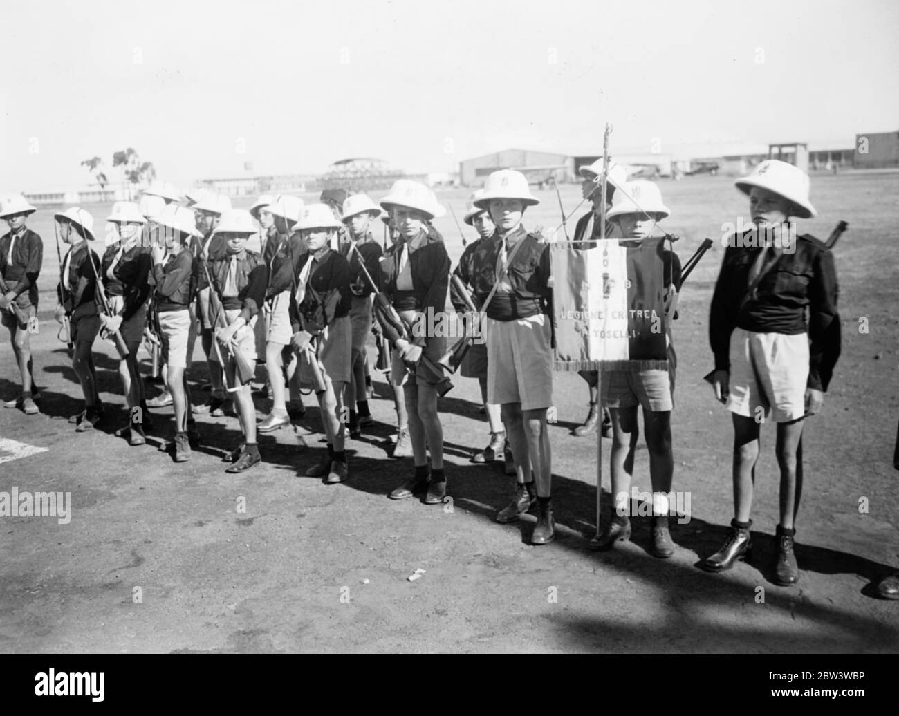 Picture by air from Italian Northern Front . Banner of the Eritrea legion of Young Fascists . Marshal de Bono reviewed the Eritrea Legion of young Fascists on the aerodrome at Asmara , the Eritrean base , before he handed over his command to Marshal Badoglio on his recall to Rome . De Bono took the salute at the march past and afterwards gave his farewell address to the troops . Photo shows , Young Fascist of the Eritrea Legion lined up for the inspection . . 3 December 1935 Stock Photo