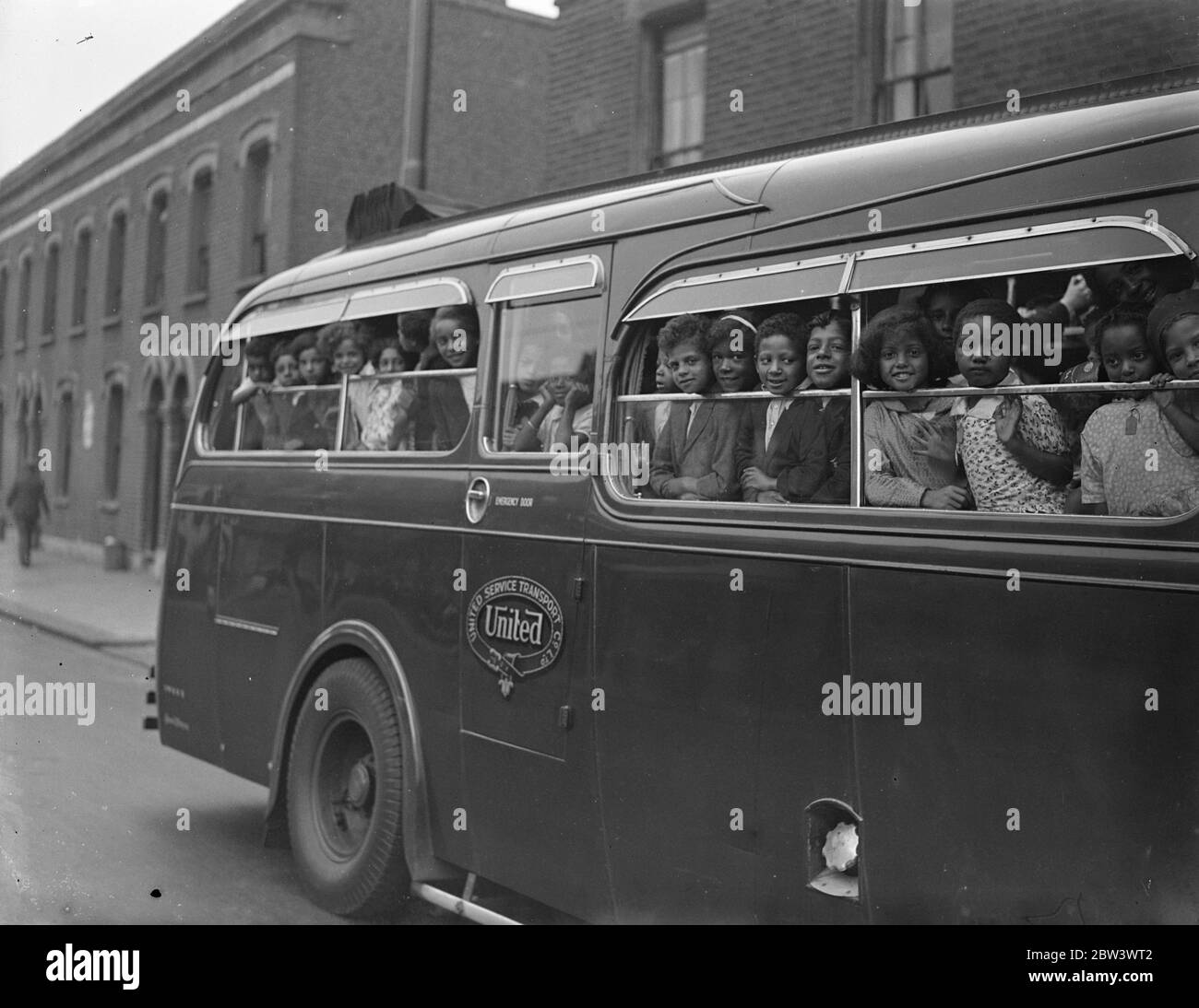Original Caption follows (1936): London coloured children have a day by the sea .A party of coloured children left Beckton Road , Canning Town , by motor coach for their annual outing to Southend . Photo shows , smiling faces in the window of the coach as the children left . 18 August 1936 Stock Photo