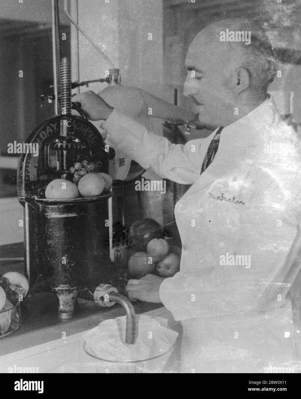 Dr A T Frascati an American scientist . Making perfume from crushed fruit . Photo shows , Dr A T Frascati crushing the fruit . Original caption from negative Stock Photo